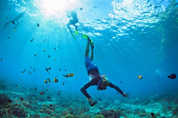 Happy family vacation. Man in snorkeling mask with camera dive underwater with tropical fishes in coral reef sea pool. Travel lifestyle, water sport outdoor adventure, swimming on summer beach holiday